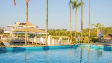 A swimming pool with a modern architectural structure in the background, surrounded by palm trees.