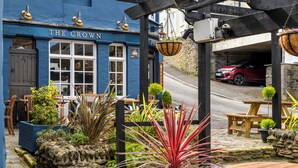 A pub named 'The Crown' with outdoor seating, stone walls, and hanging flower baskets. - The Crown Hotel (Lynton)