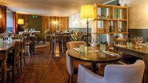 A restaurant with wooden tables and chairs, a bar area, and a bookshelf with decorative items. - The Crown Hotel (Lynton)