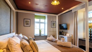A hotel room with a bed, a desk, a TV, and a window with a view. - The Crown Hotel (Lynton)