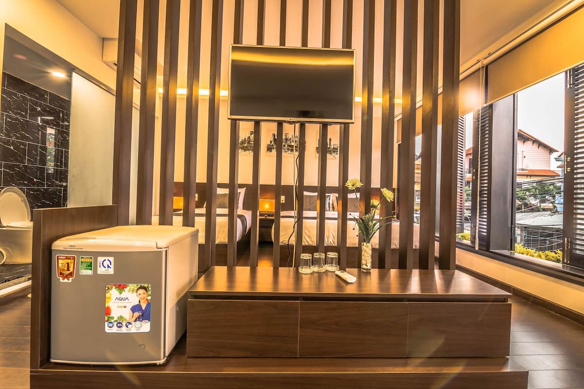 Ett modernt hotellrum med en stor TV, en minibar, en vägg av trä och utsikt över omgivningarna.