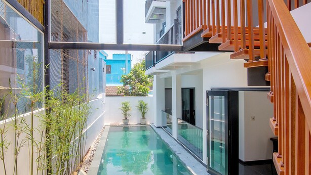 Un área de piscina interior moderna con paredes de vidrio, barandillas de madera y vistas despejadas a los edificios exteriores.
