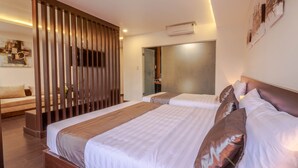Una habitación de hotel moderna con dos camas, un separador de madera, un sofá y un espejo grande.
