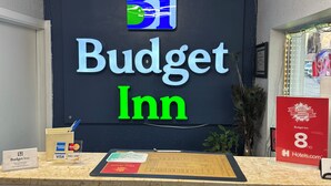 A reception desk with a sign for Budget Inn, a security camera, and a framed award.