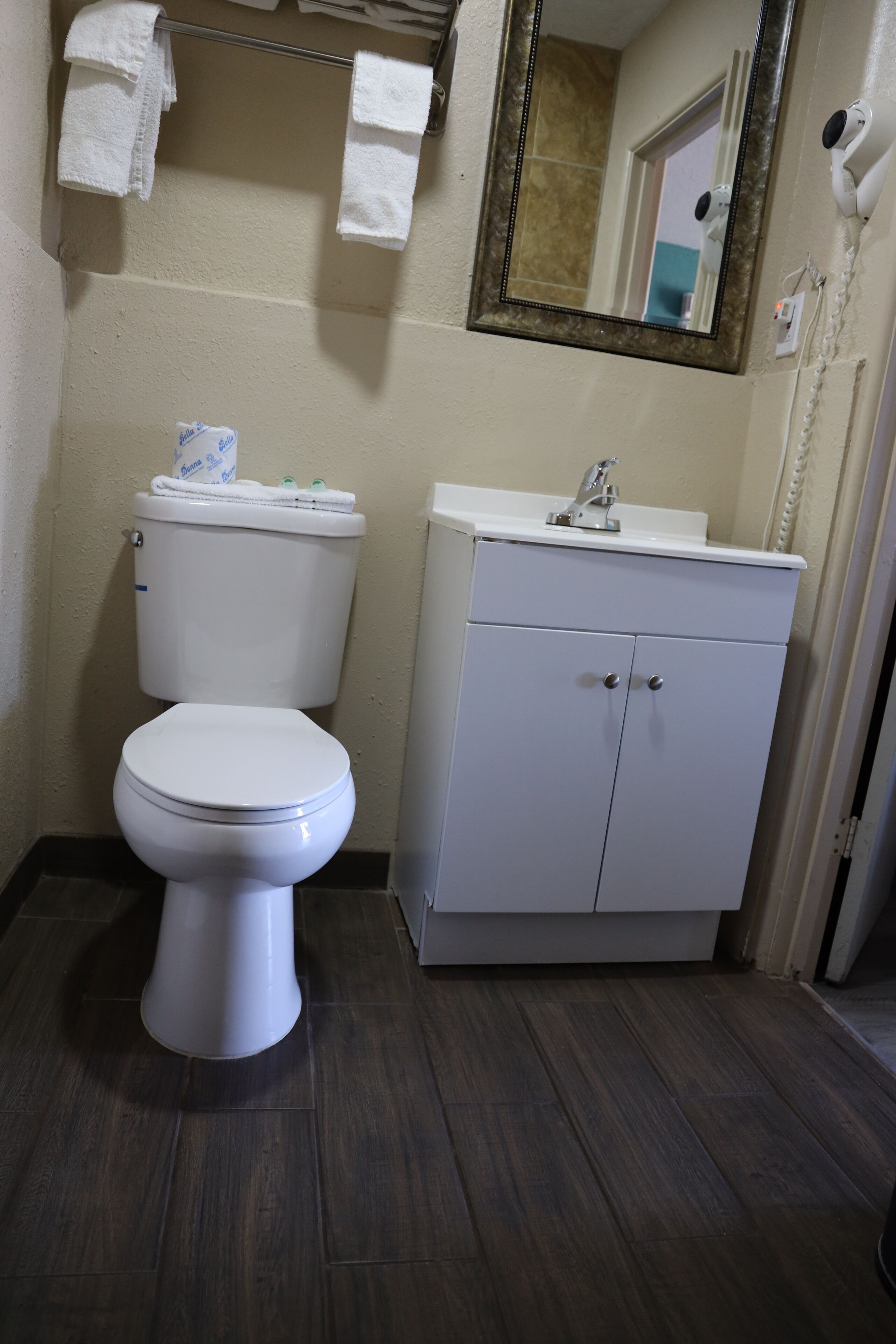 A bathroom with a white toilet, a sink with a mirror above it, and a cabinet below.
