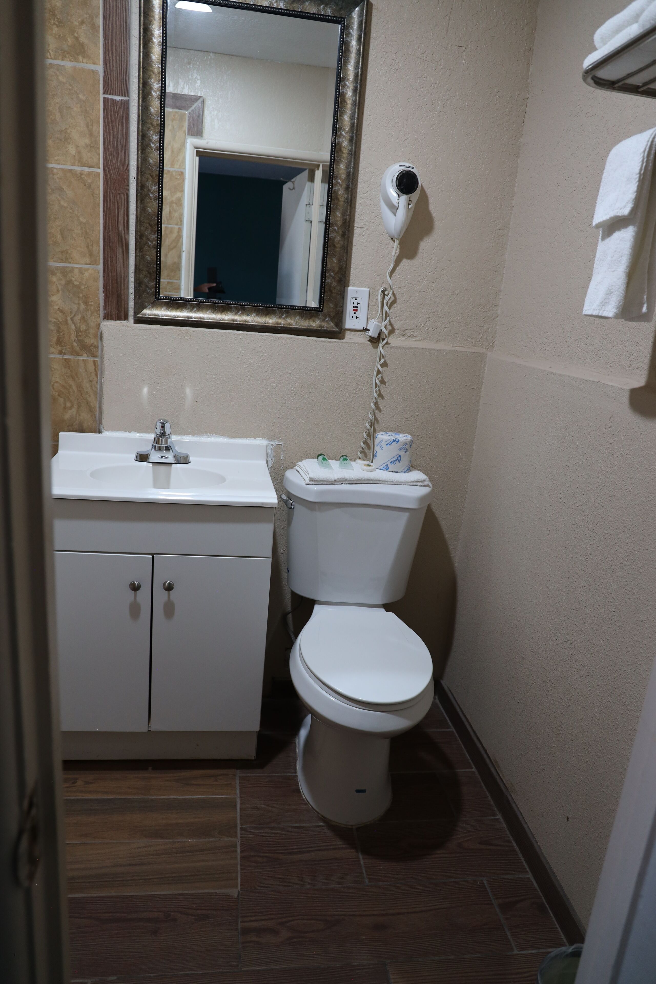 A bathroom with a sink, toilet, and a hairdryer mounted on the wall.
