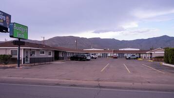 A Budget Inn with a parking lot, a mountain backdrop, and a clear sky.