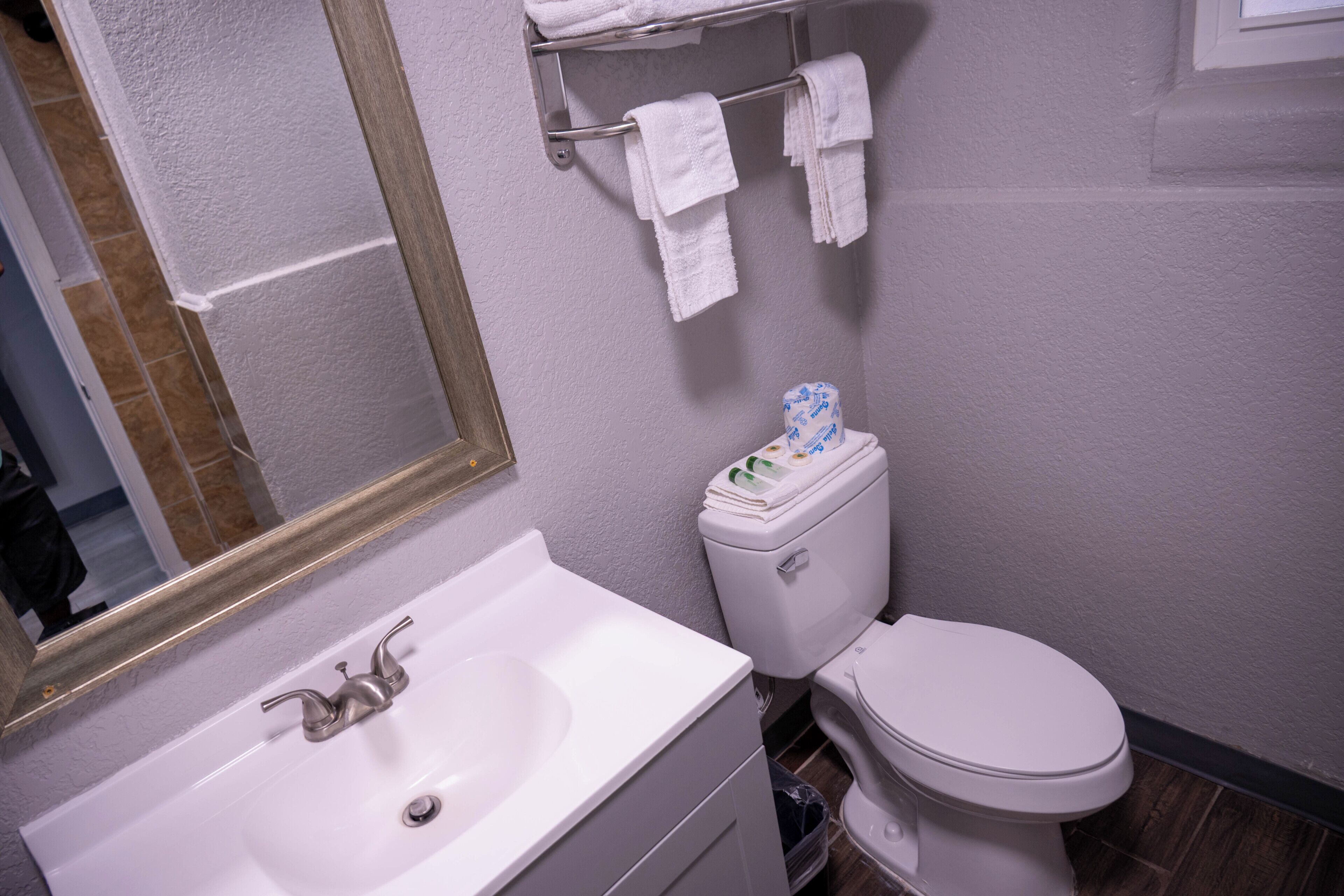 A bathroom with a sink, mirror, towel rack, and toilet.
