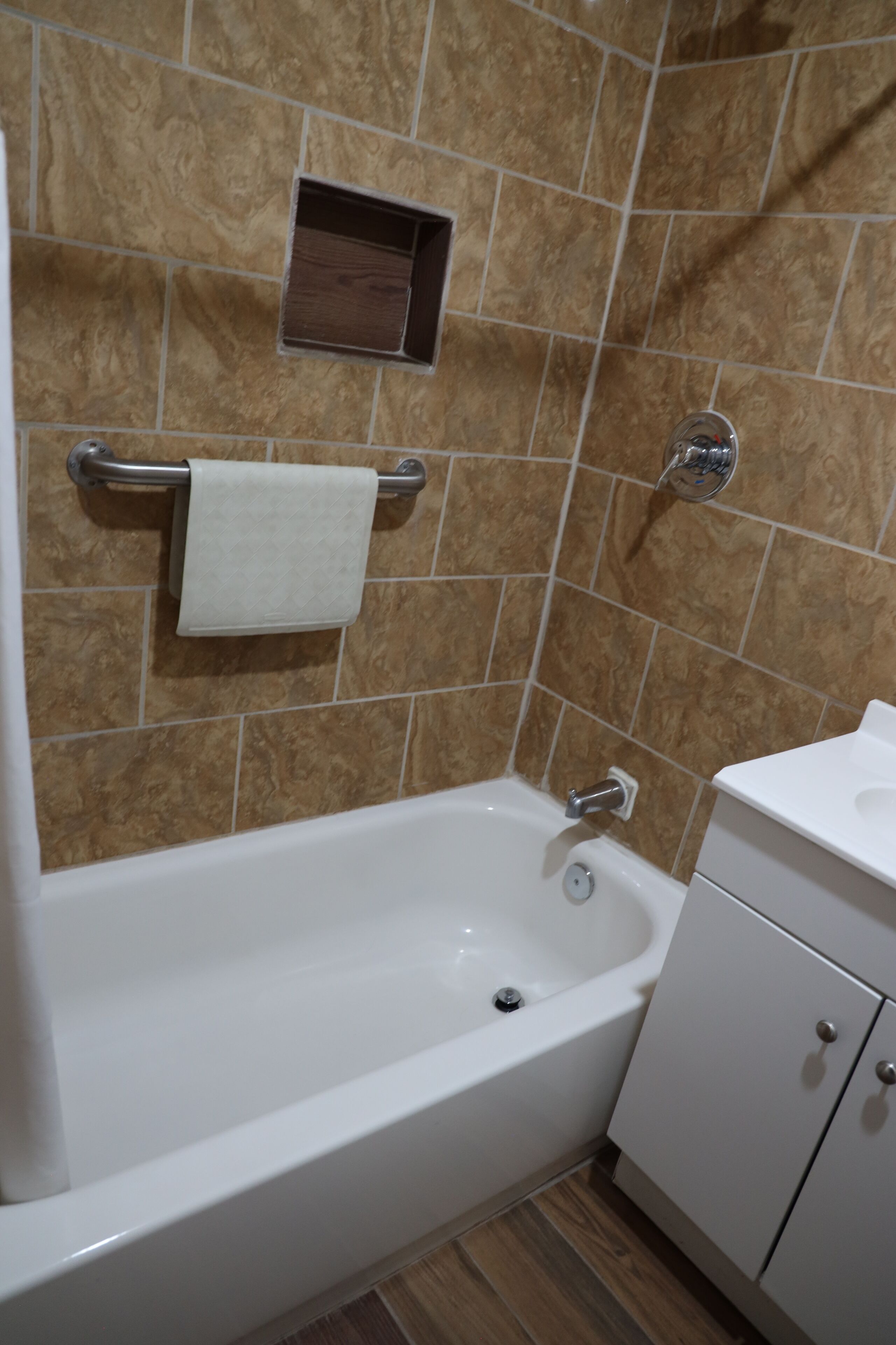 A bathroom with a bathtub, a towel rack, a sink, and a cabinet.