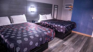 A hotel room with two beds, a clock, and an air conditioning unit.