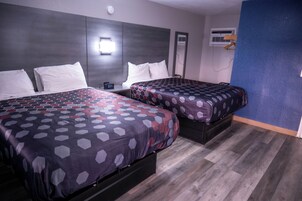 Habitación de hotel con dos camas, un reloj y un equipo de aire acondicionado.
