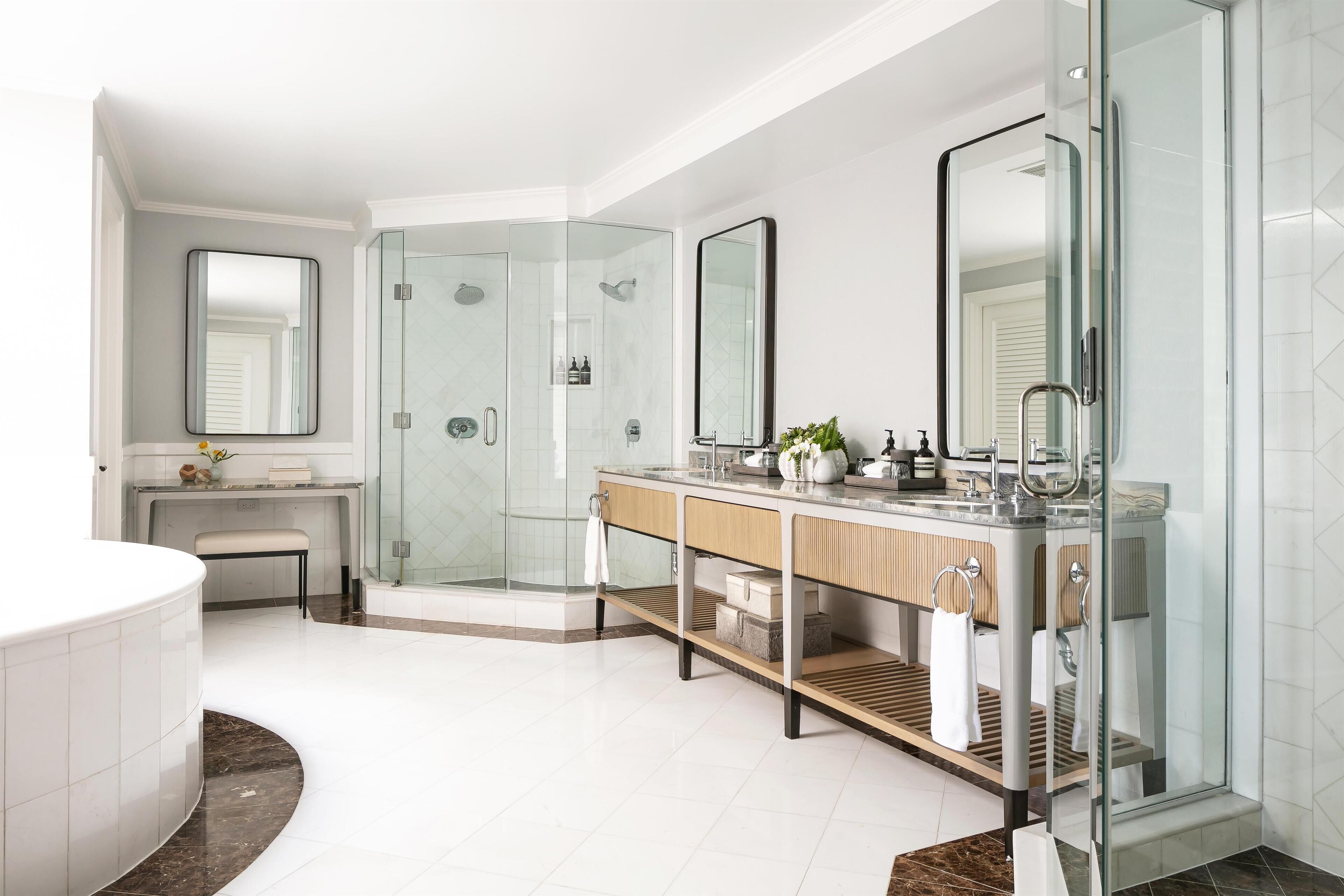 Un baño moderno con ducha envuelta en vidrio, tocador con espejo y bañera.
