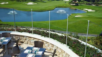Enjoy a peaceful meal with a view of the golf course and tranquil pond from this serene outdoor dining area.