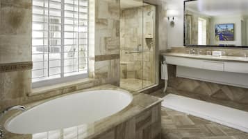 A modern bathroom with a freestanding bathtub, a glass-enclosed shower, and a vanity with a large mirror.