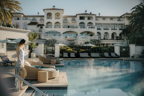 Ein Poolbereich mit Liegestühlen und einem großen Gebäude im Hintergrund.