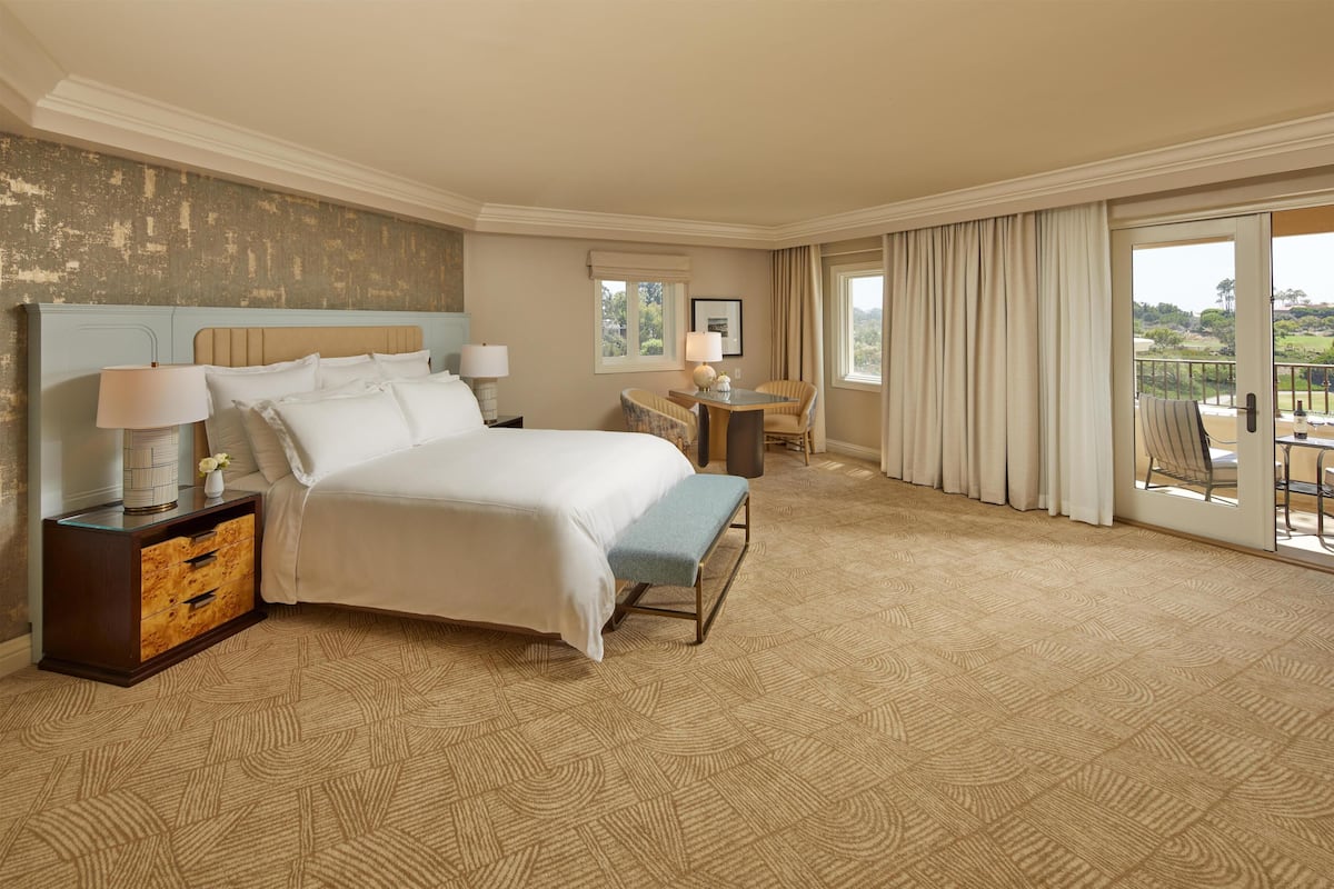 Habitación de hotel con una cama grande, un escritorio y vistas al exterior.