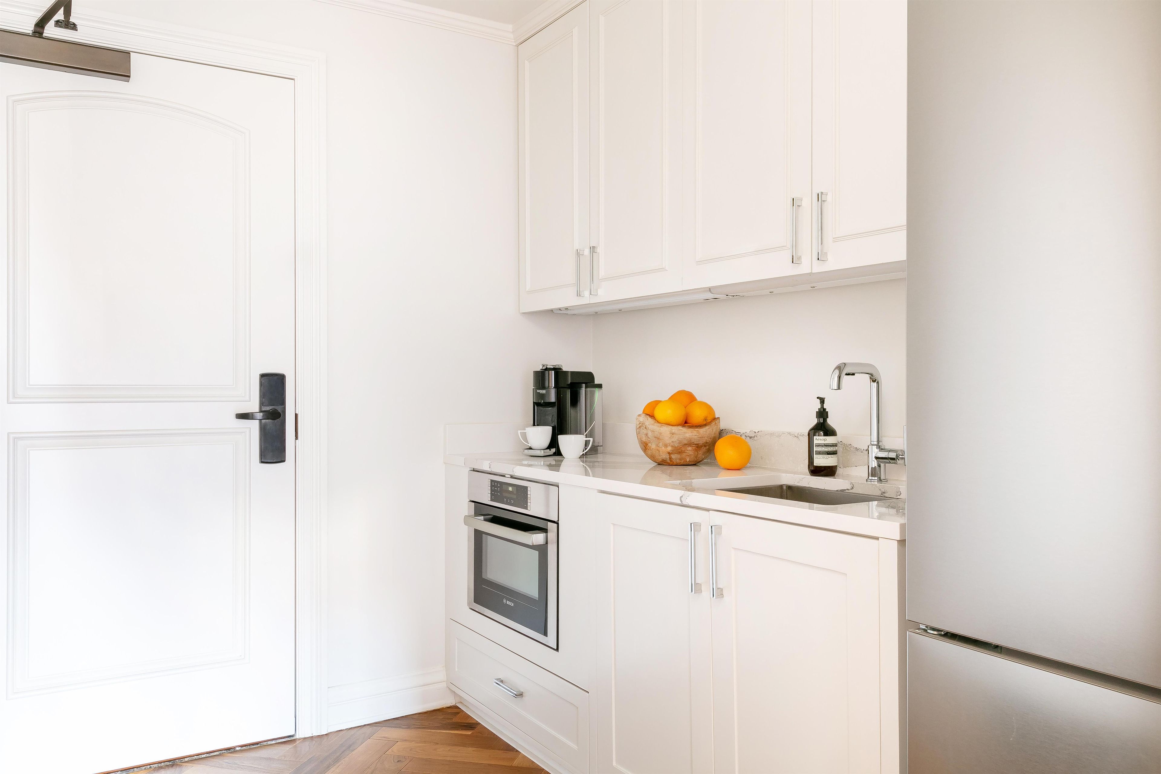 A compact kitchen with white cabinetry, a built-in oven, and a sink.