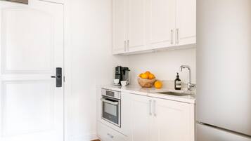 Une cuisine compacte avec des meubles blancs, un four encastré et un évier.