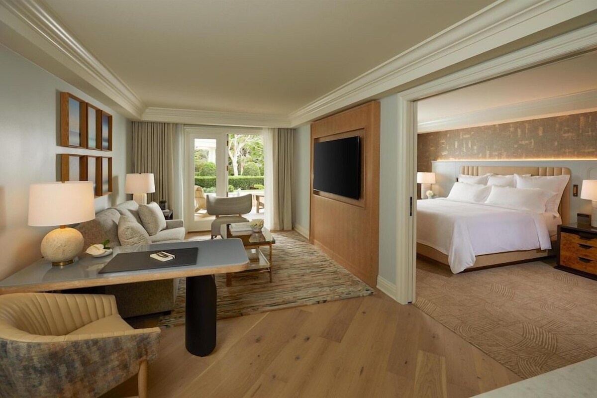 Una habitación de hotel con cama, escritorio, silla y televisión.
