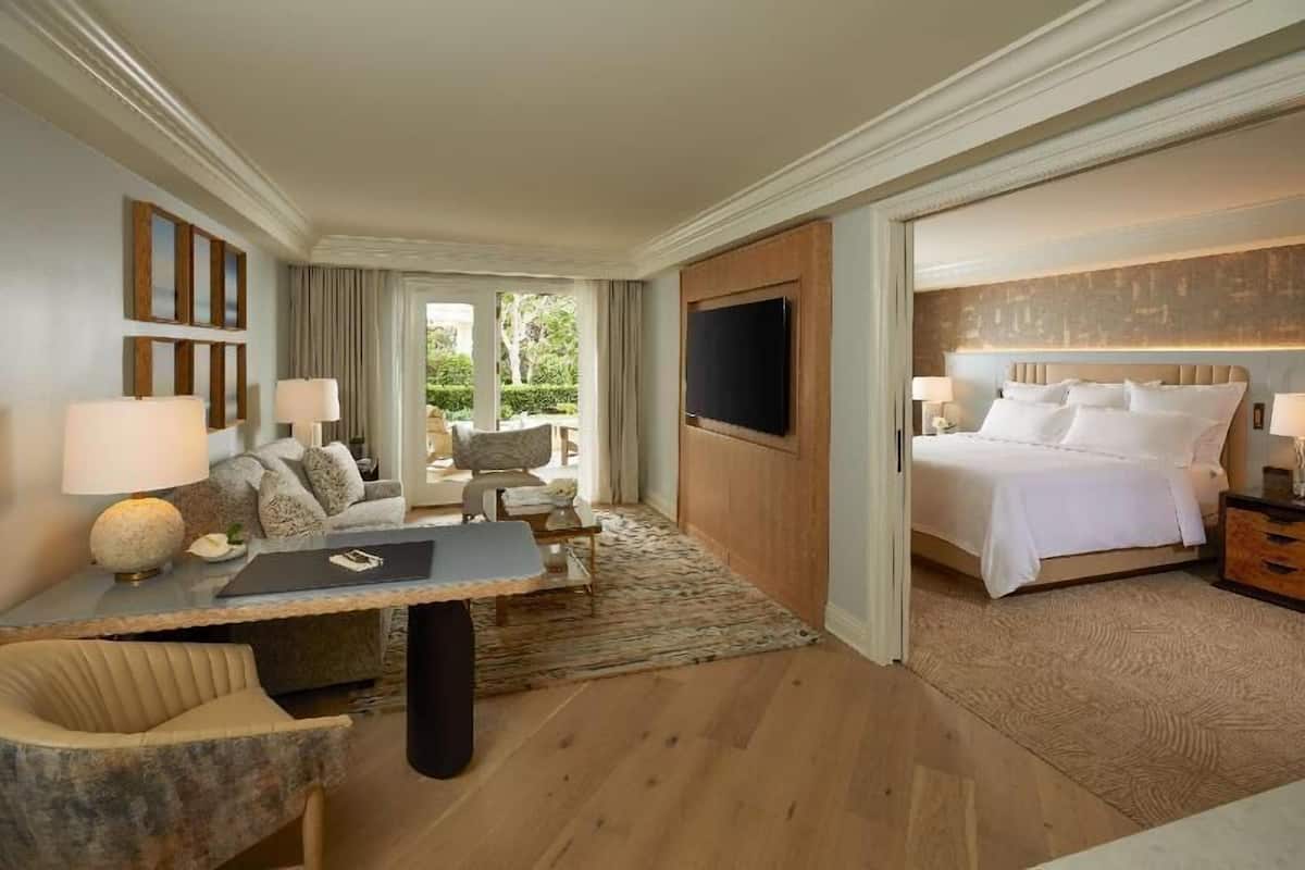 Habitación de hotel con cama, escritorio con silla, televisor y vistas al exterior.