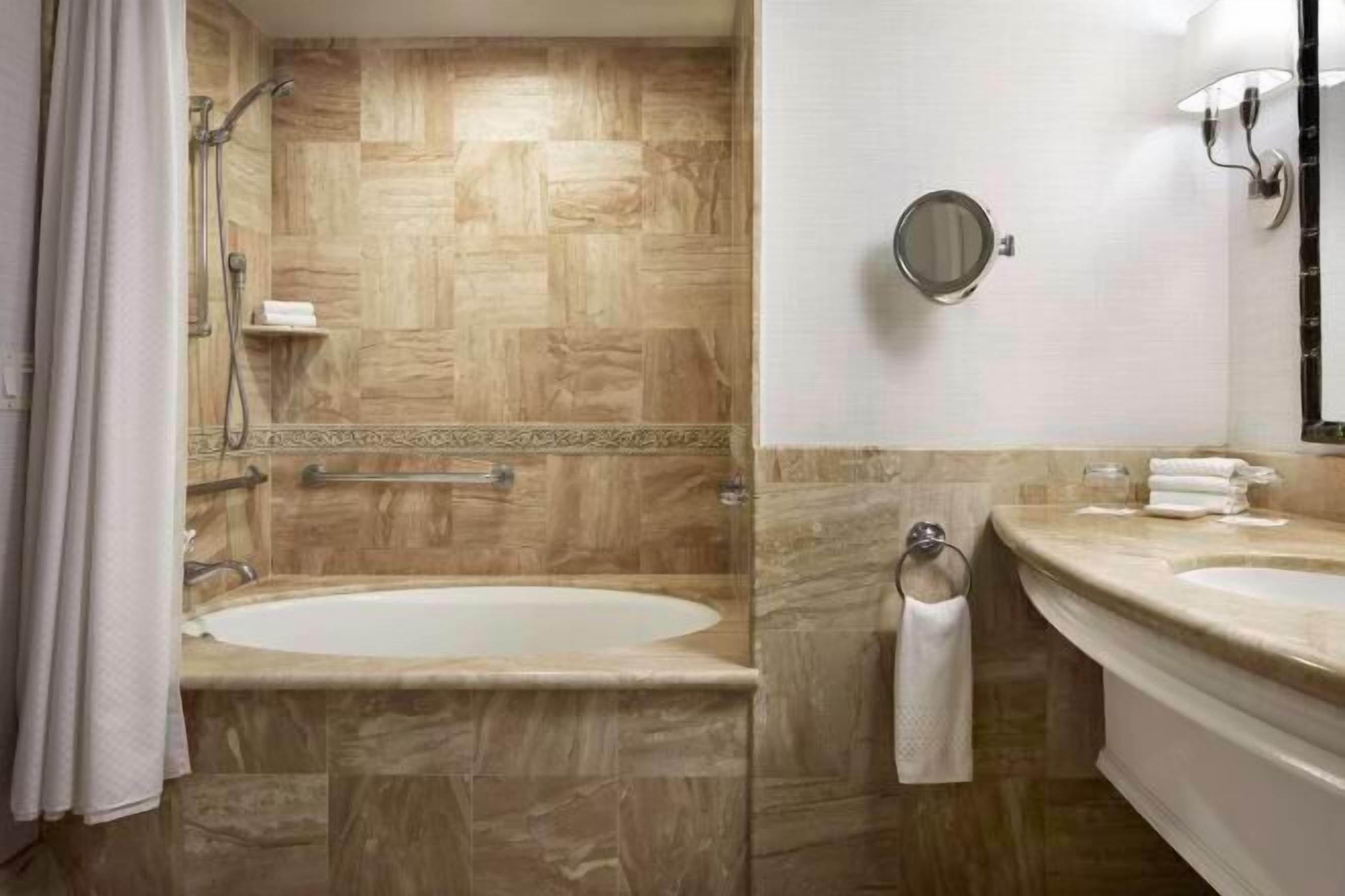 Een aparte badkuip en douche, een diep bad, designer toiletartikelen