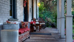 Une terrasse en bois avec un espace salon extérieur comprenant un banc et des chaises, ainsi qu’un grand bac à plantes.