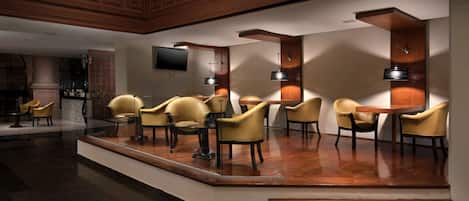A lobby with a reception desk, seating area with chairs, and a television mounted on the wall.