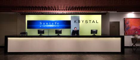A reception desk with a sign reading "Santa Fe Group Motelero" and "KRYSTAL."