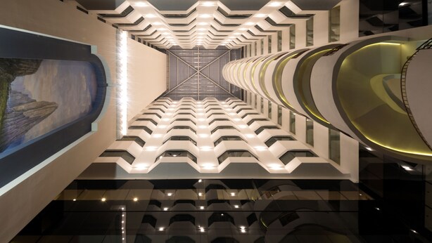A modern interior with a geometric ceiling design, a central light fixture, and a reflective floor. - Krystal Monterrey (Monterrey)