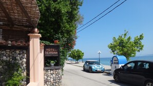 Un hotel costero llamado "HOTEL DESPOINA" con fachada de piedra, plantas en macetas y vistas despejadas al mar.