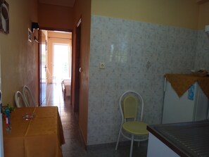 A kitchen with a dining table, chairs, a refrigerator, and a chair with a yellow seat. - Despoina Hotel (Istiaia-Aidipsos)