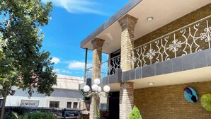 A courtyard with outdoor seating, a brick wall, and a balcony with decorative railing. - Autel Rio Inn Luxury Inns (Piedras Negras)