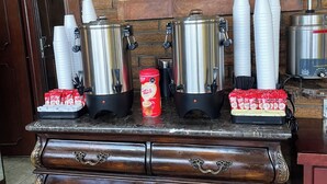 A coffee station with multiple coffee dispensers, cups, and a coffee maker. - Autel Rio Inn Luxury Inns (Piedras Negras)