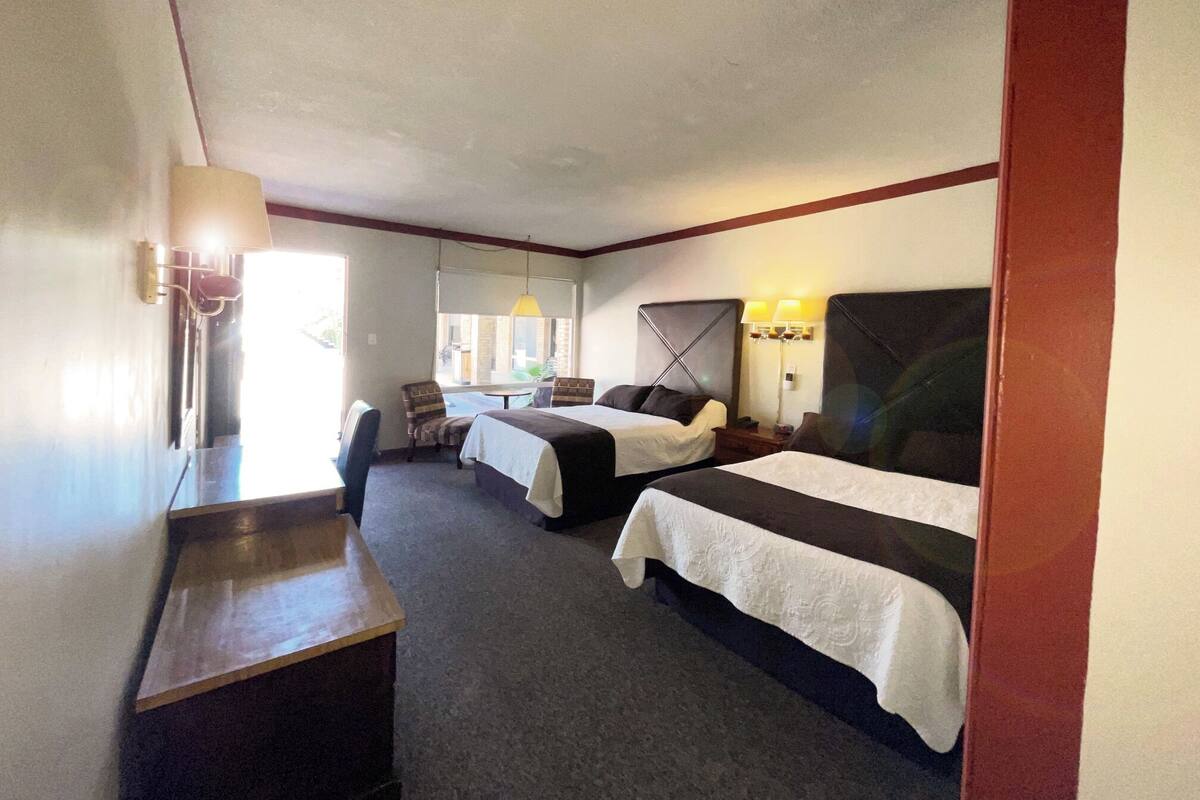 A hotel room with two beds, a desk, and a chair.
