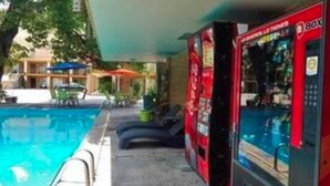 A pool area with lounge chairs and a red vending machine. - Autel Rio Inn Luxury Inns (Piedras Negras)