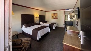 A hotel room with two beds, a small kitchenette, a television, and a patterned ottoman. - Autel Rio Inn Luxury Inns (Piedras Negras)