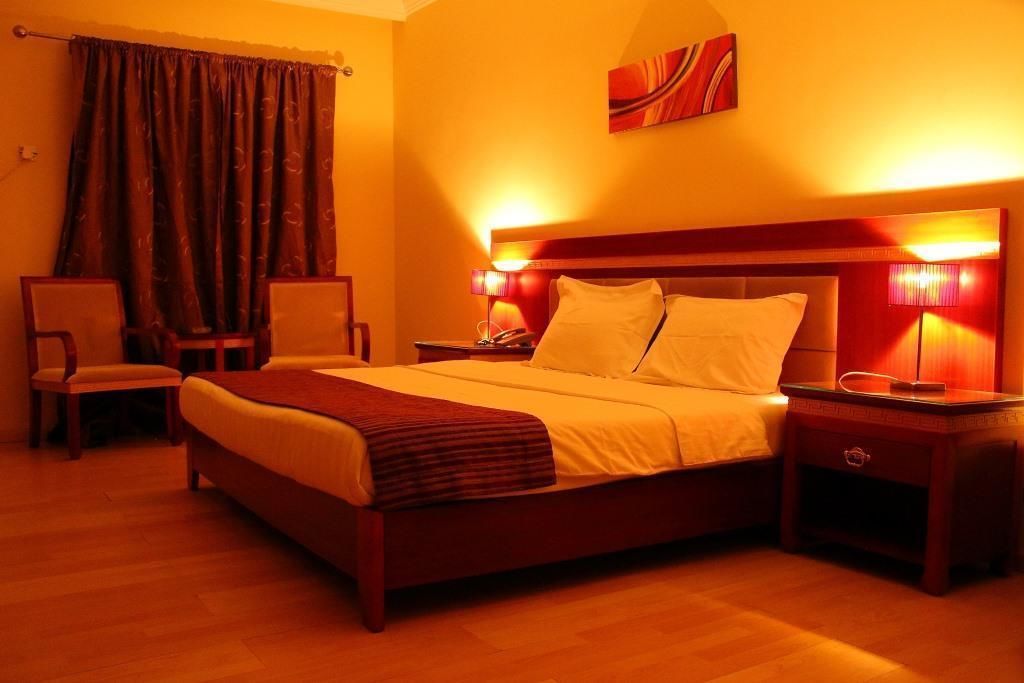 A hotel room with a large bed, two bedside tables, a chair, and a painting on the wall.