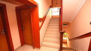 A staircase with wooden handrails and a door labeled "302" leading to a room. - Hotel Rosebud (Abuja)