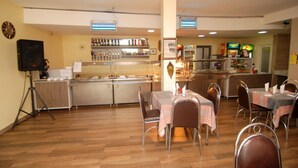 A restaurant with a bar area, multiple tables, and chairs. - Hotel Rosebud (Abuja)