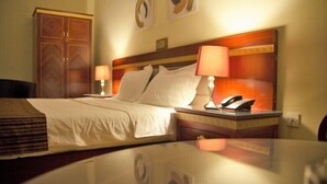 A hotel room with a bed, two bedside lamps, a nightstand with a telephone, and a wardrobe. - Hotel Rosebud (Abuja)
