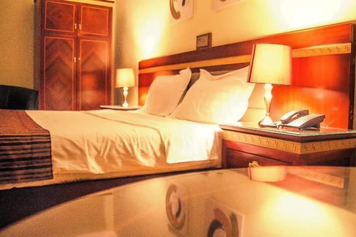 A hotel room with a bed, two bedside tables with lamps, a telephone, and a mirror.