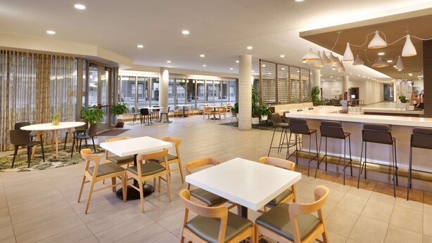 A spacious indoor area with multiple seating arrangements, including tables and chairs, and a central bar area. - Hyatt House Portland/Downtown (Portland)