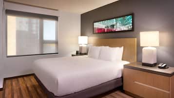 Habitación de hotel con una cama grande, dos lámparas de noche, una mesita de noche con teléfono y un televisor montado en la pared.