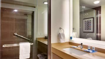 A modern bathroom with a glass shower enclosure, a vanity with a sink, and a large mirror.