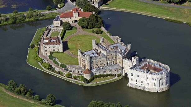 Un extenso complejo de castillos históricos con varios edificios, un foso y un lago.