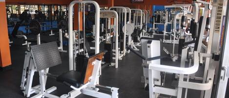 Un gimnasio con diversas máquinas de ejercicio y equipamiento para levantamiento de pesas.