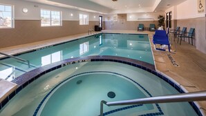 Una piscina interior con agua cristalina, borde de azulejos y un elevador para piscina.