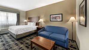 A hotel room with a bed, a blue sofa, a wooden coffee table, and two bedside lamps. - Best Western Plus Big Lake Inn (Big Lake)
