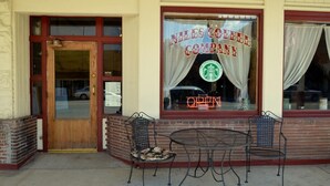 En butik med en trädør, et skilt der siger "Niles Company", og et Starbucks-logo, der angiver en kaffebar indeni. Der er to metalstole og et lille rundt bord udenfor.