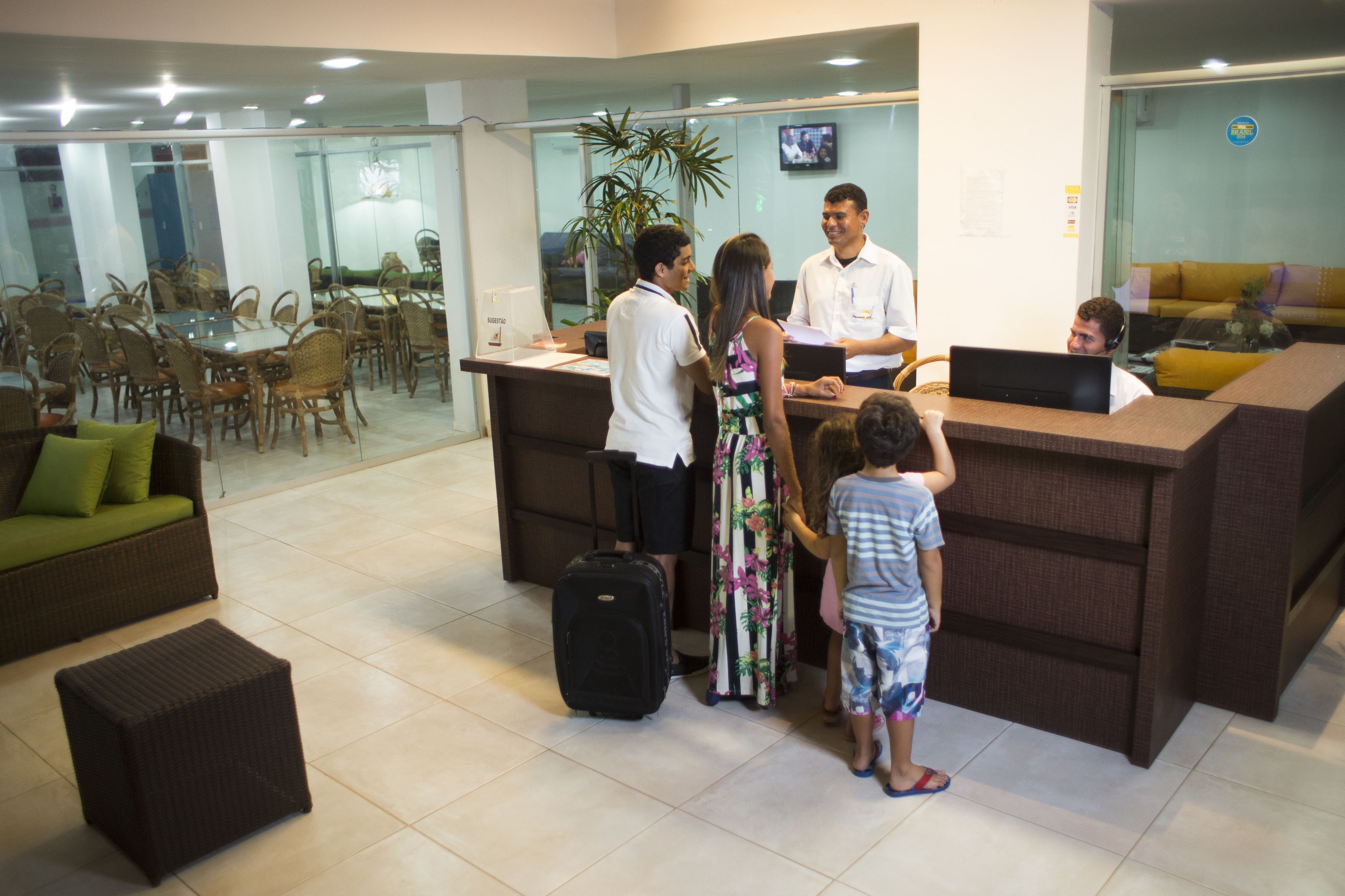 Un área de recepción con mostrador, sillas, un sofá y un comedor con mesas y sillas.